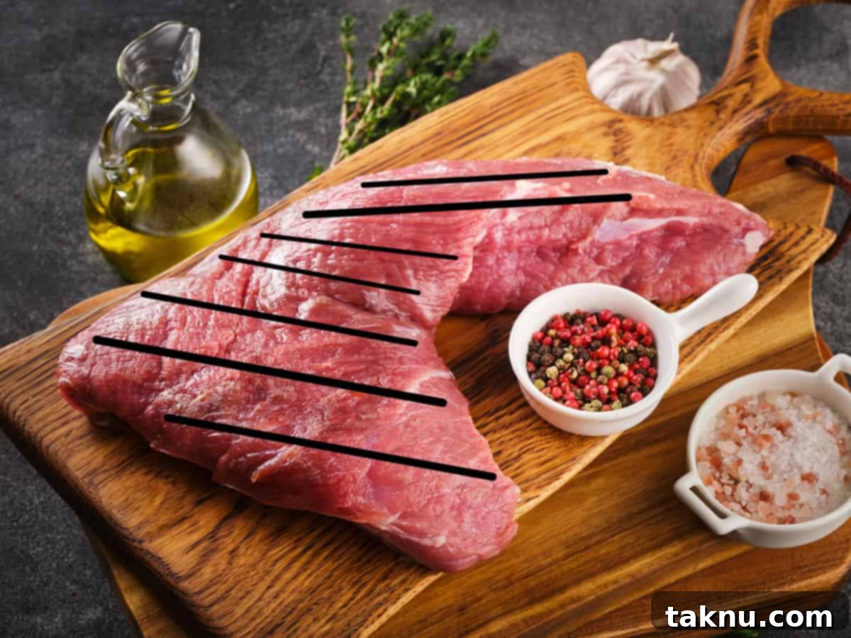 Cooked tri-tip steak with black lines indicating the two different directions of the meat grain for proper slicing.