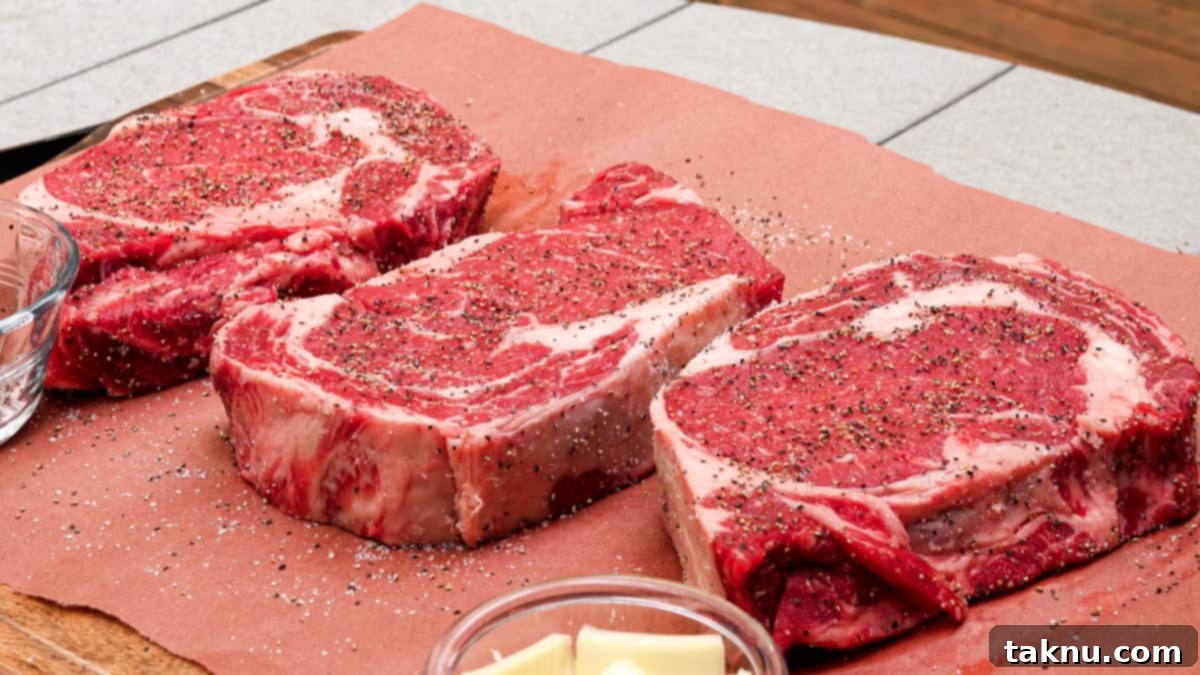 Ultimate Smoked Ribeye 4 Three thick-cut ribeye steaks generously seasoned with salt and pepper, ready for the smoker.