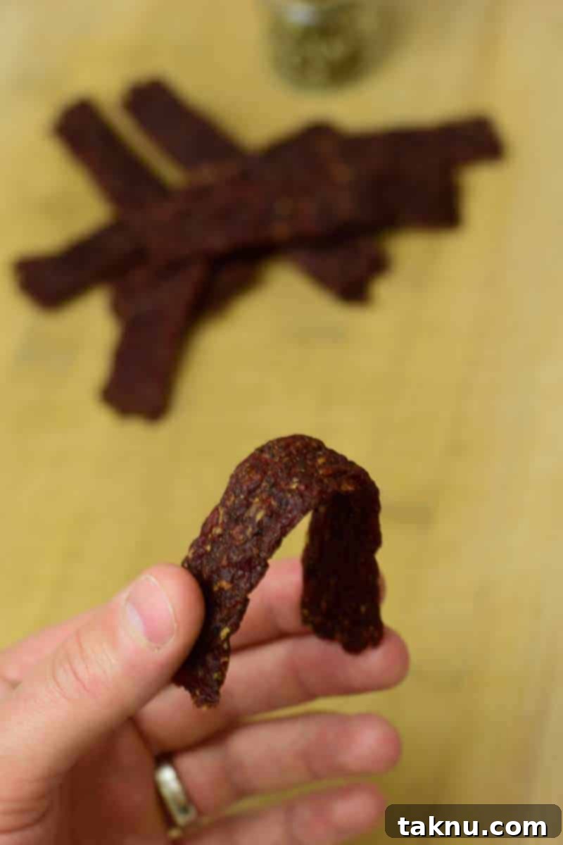 Testing homemade ground beef jerky for perfect doneness: bending without breaking, indicating a soft and chewy texture.